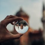 A hand holds a lensball capturing an inverted historic building in Istanbul, creating a dreamy effect.
