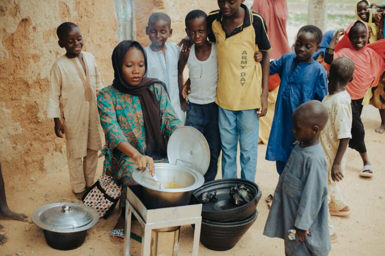 Woman cooking with children around in an outdoor setting.